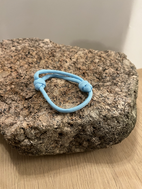 Lyseblått armbånd med dobbel knute til justering